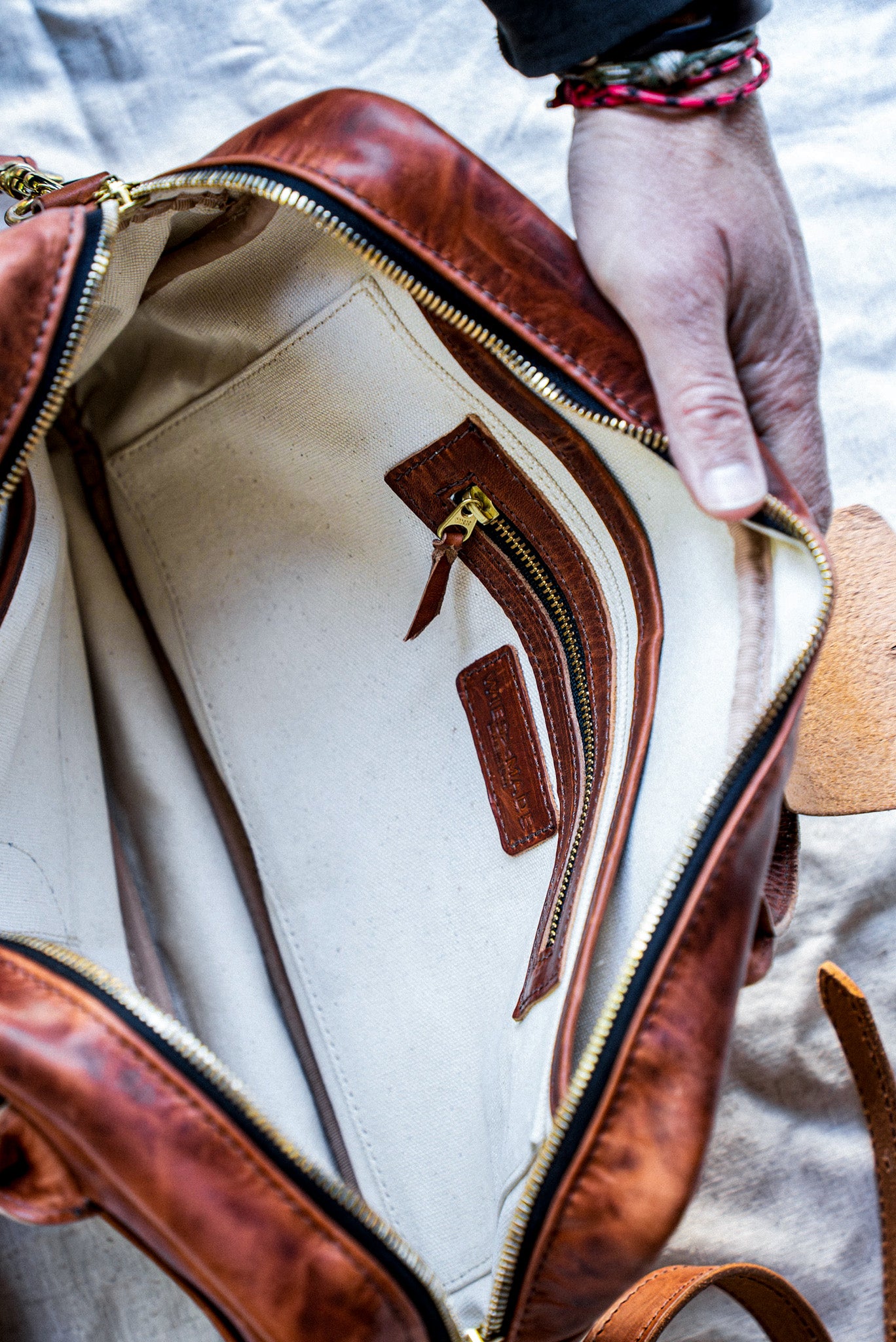 Interior of tan Horween leather brief bag with natural cotton canvas lining and brass zip pocket.