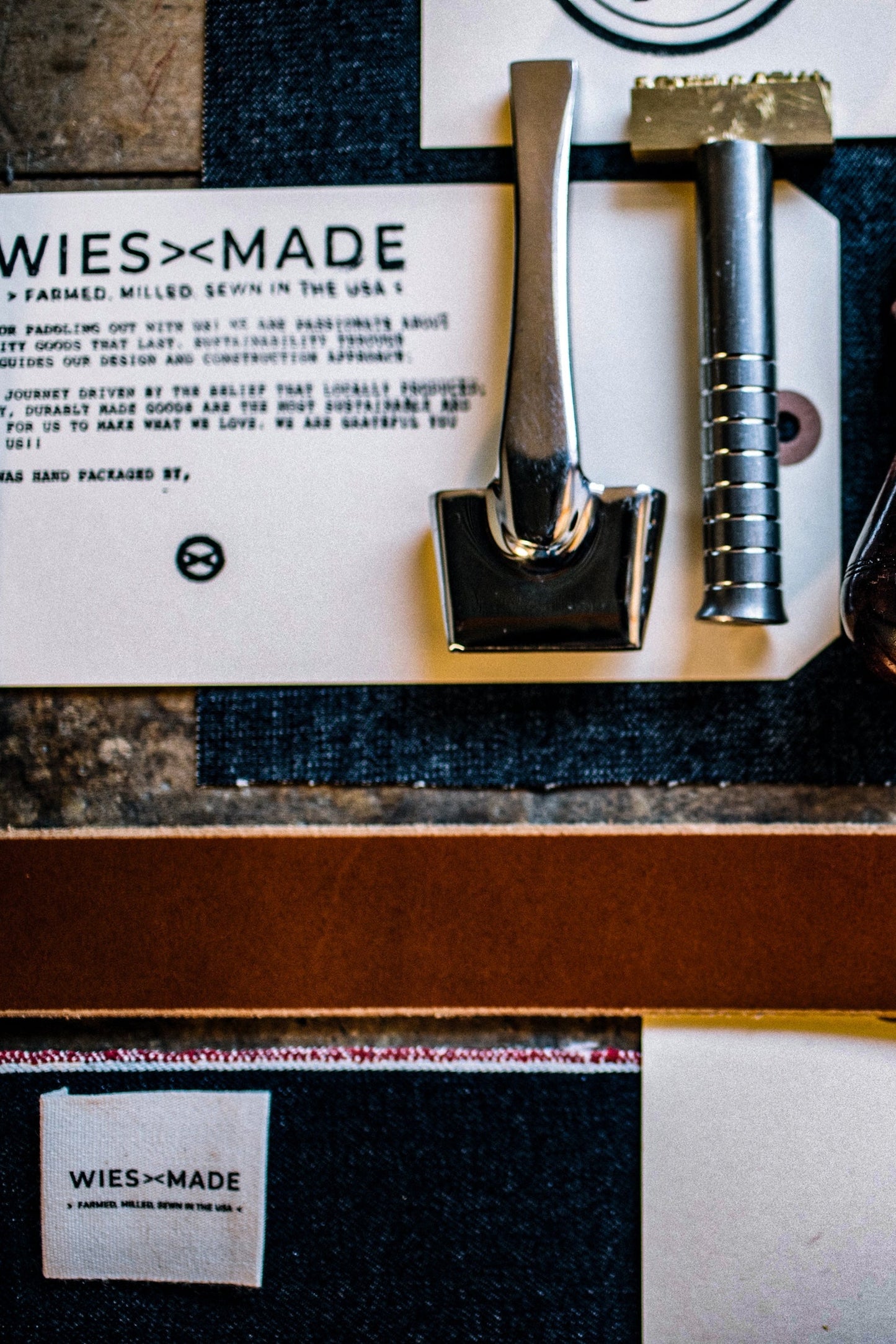 Tan Horween leather key clip with brass hardware and leatherworking tools on selvedge denim.