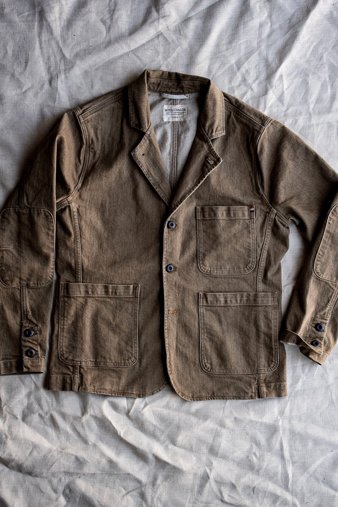 Wheat denim chore blazer laid flat, showing patch pockets, notch lapel and button front.