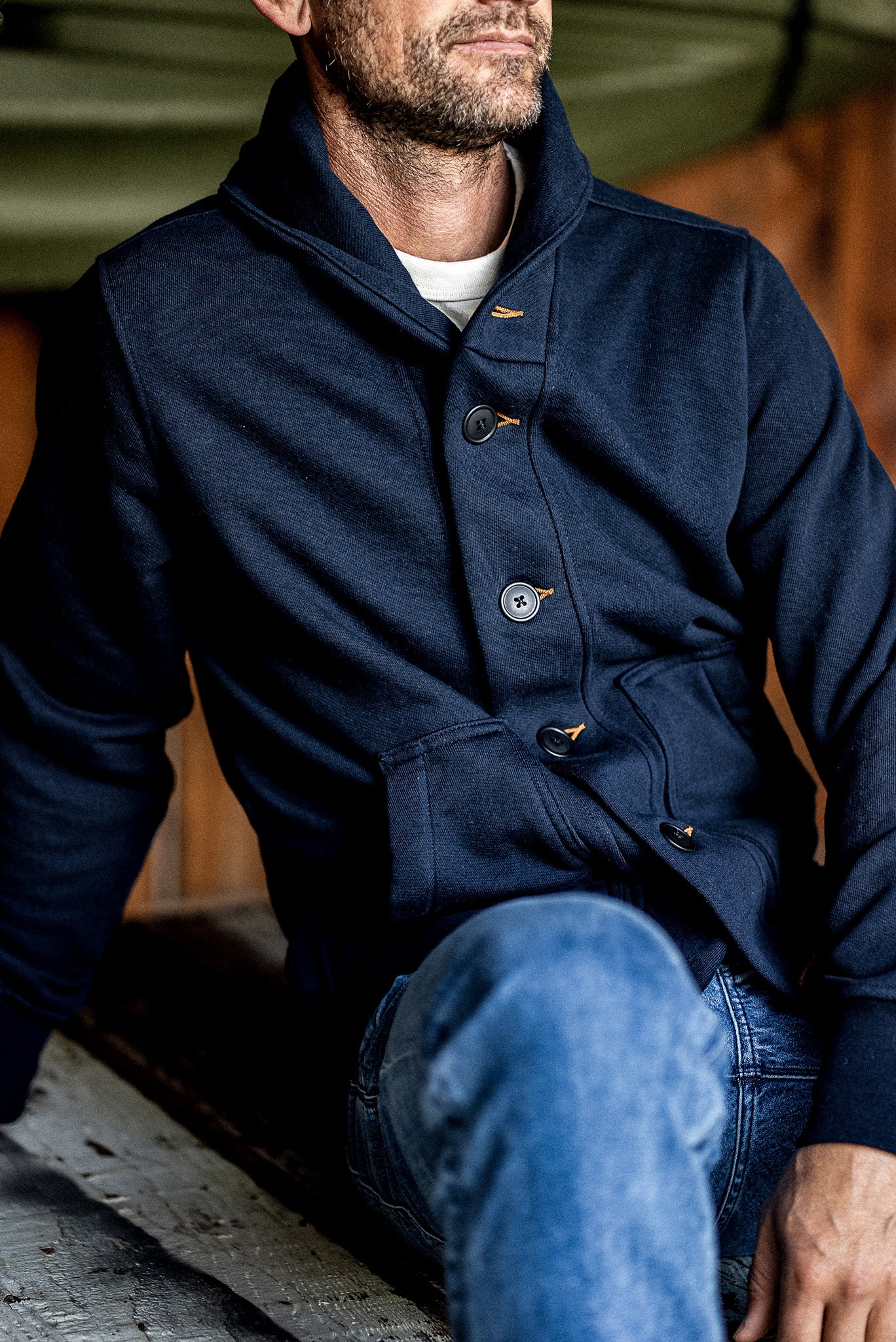 Navy Bodega shawl-collar cardigan worn on-model with contrast tobacco keyholes over blue jeans.