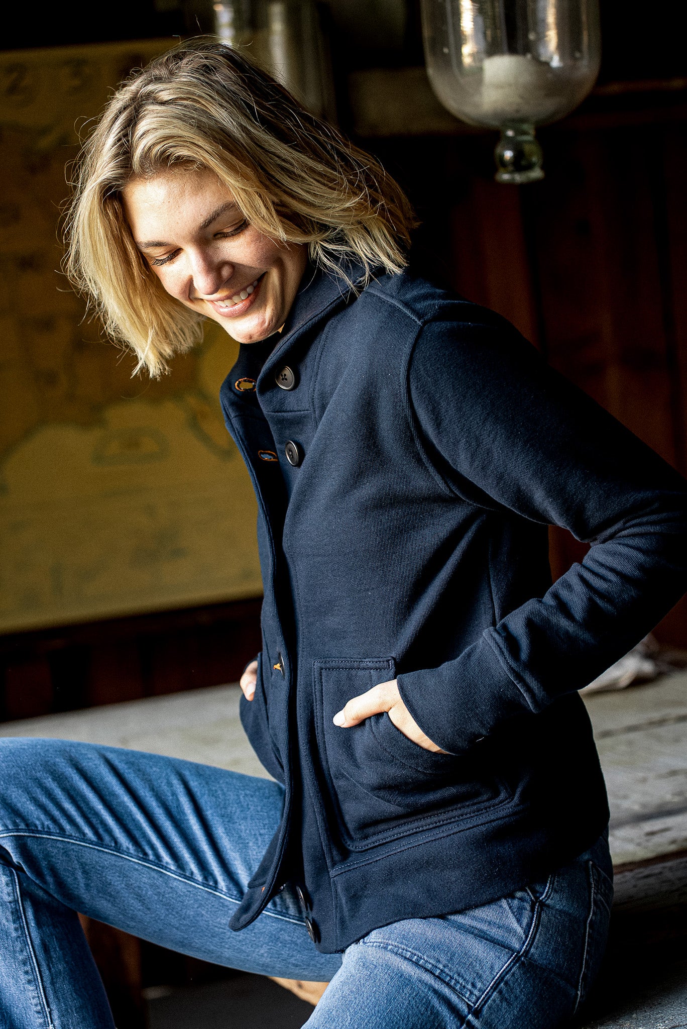 Navy French terry Bodega cardigan worn buttoned with hands in front pockets.