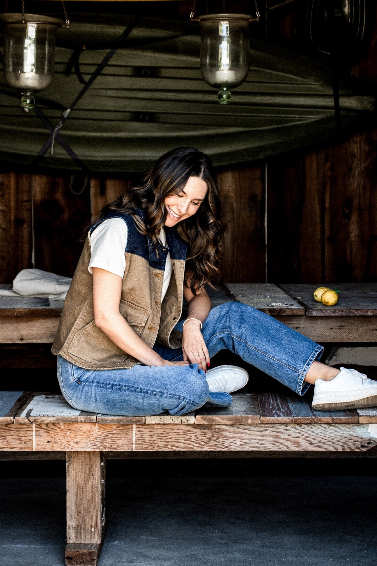 Woman in a wheat broken twill denim vest sitting on a wooden bench.