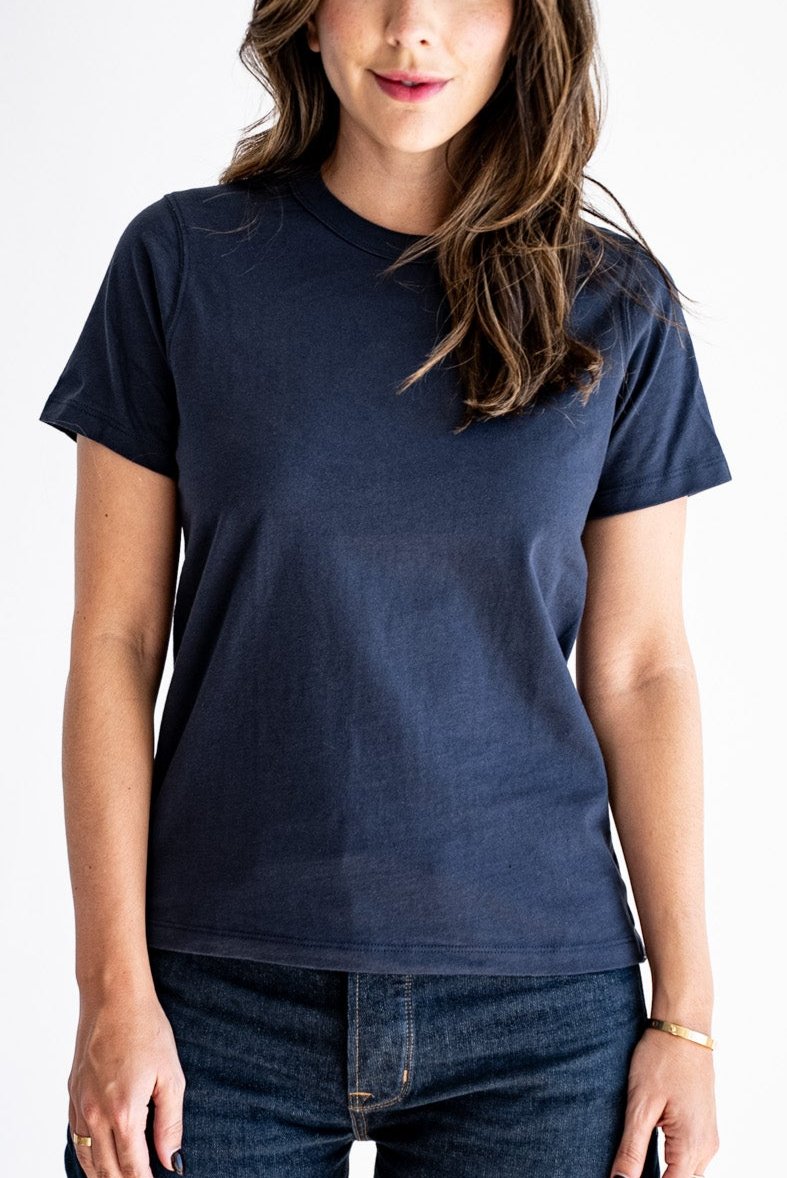 Woman wearing a relaxed-fit boxy cotton tee in dark navy, paired with denim jeans.