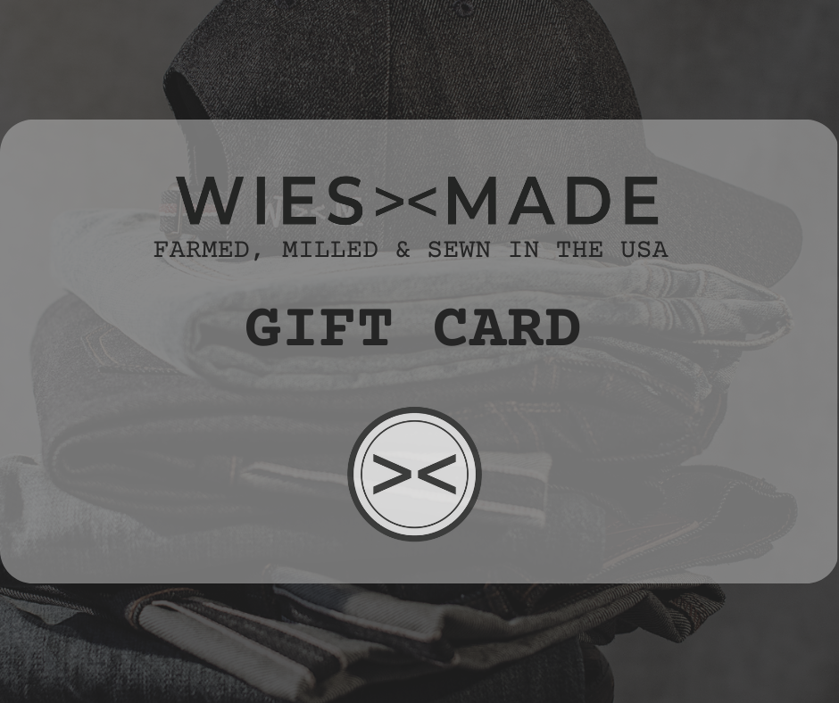 WiesMade gift card with folded denim jeans and cap in the background.