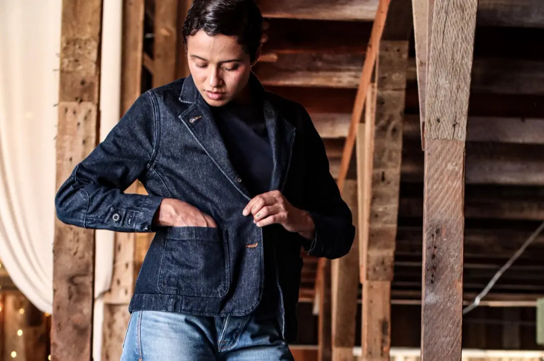 Broken twill denim jacket with visible stitching details worn by a person reaching into the front pocket.