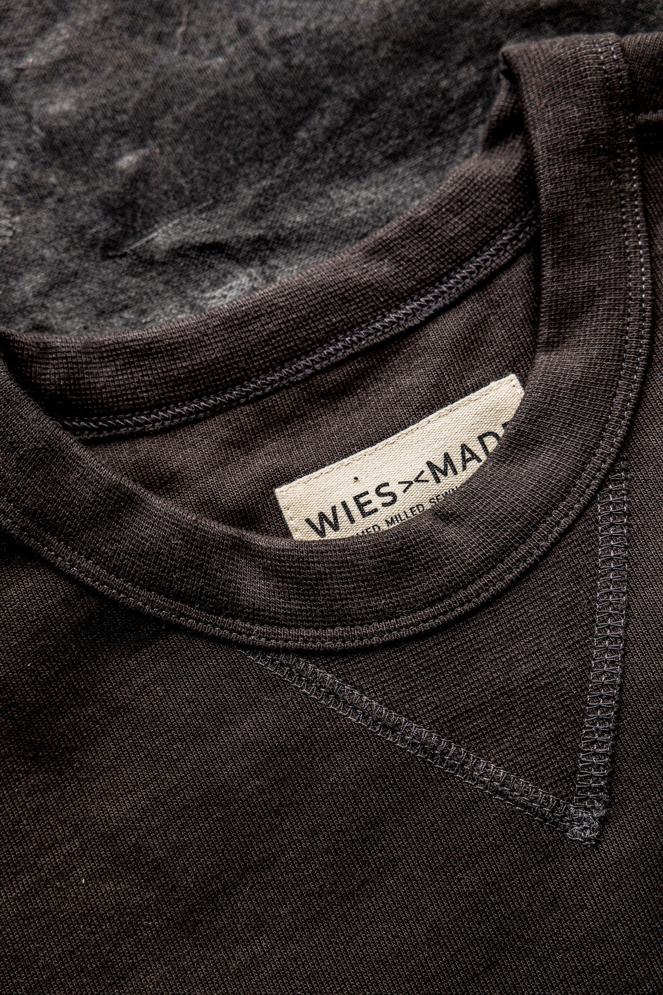 Close-up of basalt rugby jersey pullover's ribbed crew neckline, double-stitched seams, and WiesMade label.