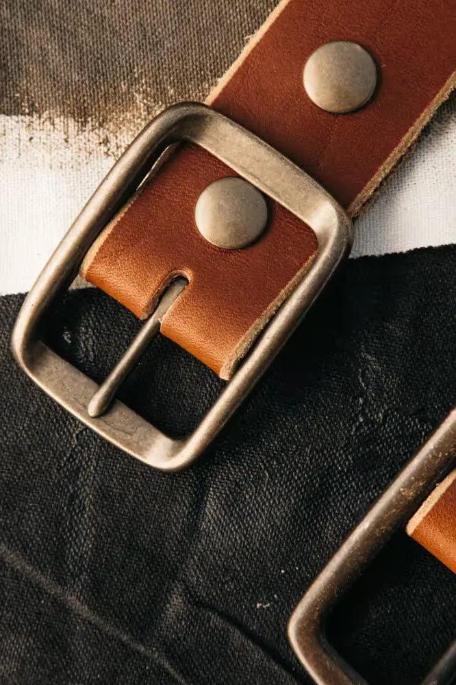 Latigo Belt in 1.5” width, crafted from 8oz American Latigo Leather with a brass buckle, displayed on a black fabric background
