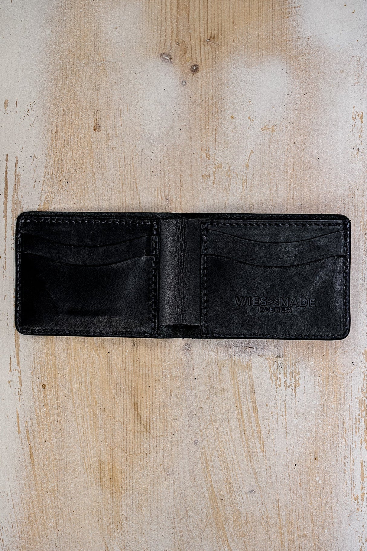 Open black Horween leather bi-fold wallet showing card slots and Made in USA stamp.