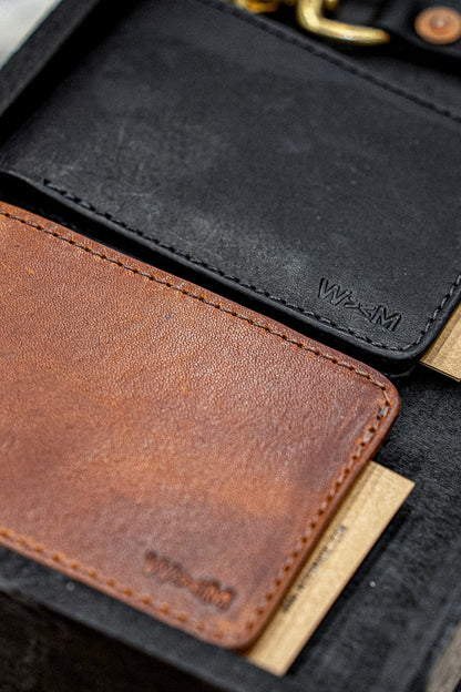 Black Horween leather bi-fold wallet beside a tan card holder with embossed WiesMade logo.