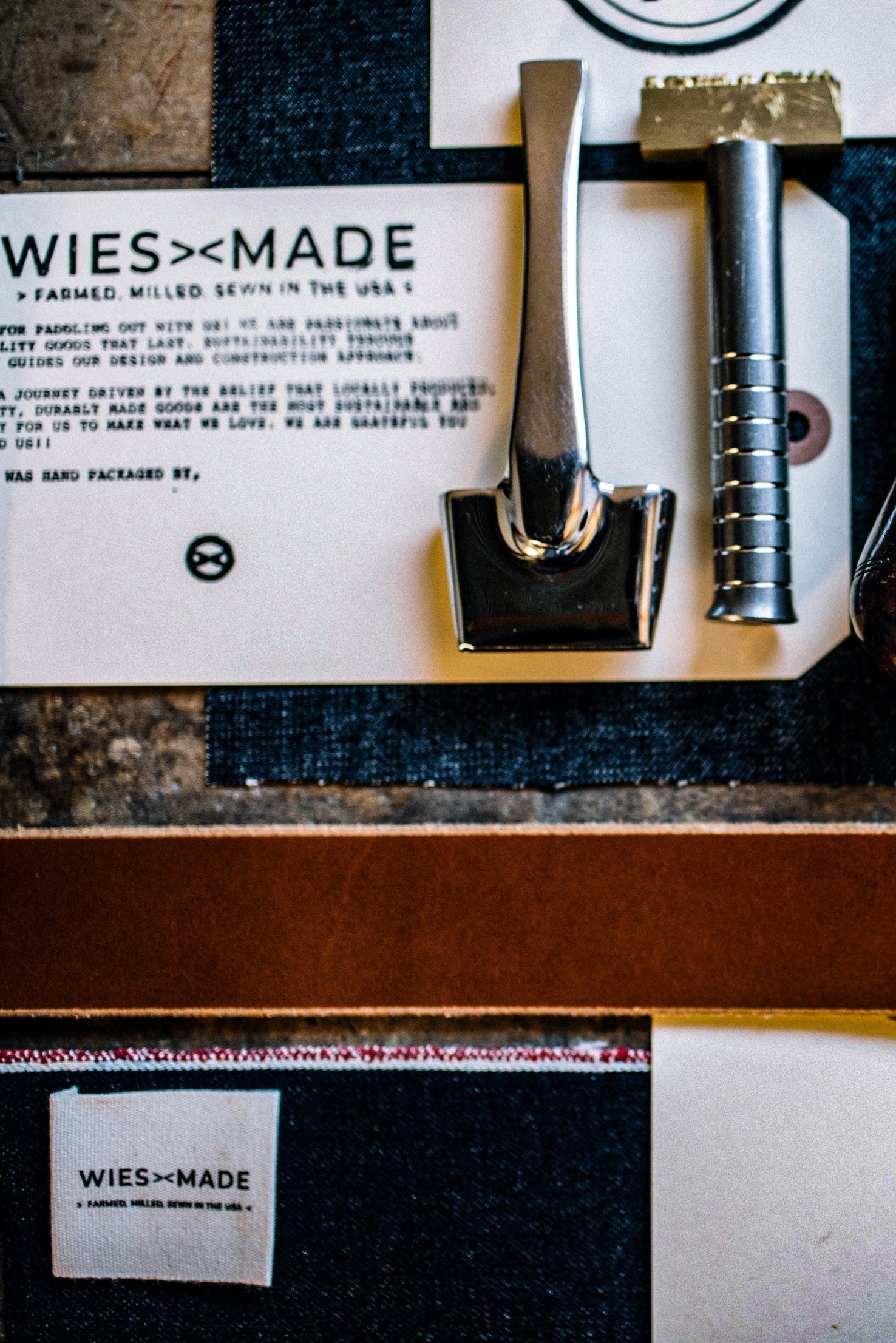 WiesMade branded card and leather stamping tools laid over selvedge denim made in USA.