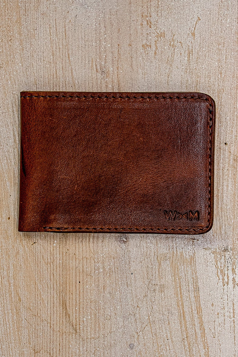 Tan Horween leather bi-fold wallet with embossed WiesMade logo on weathered wood.