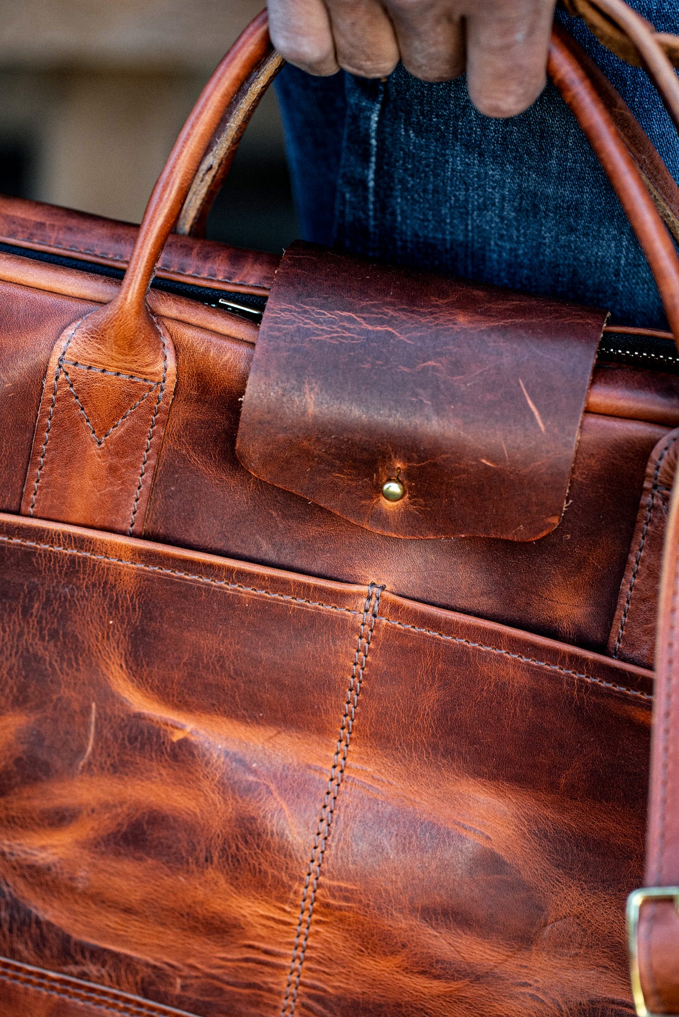 Tan Horween leather briefcase with front snap pocket, brass hardware, and rolled top handles.