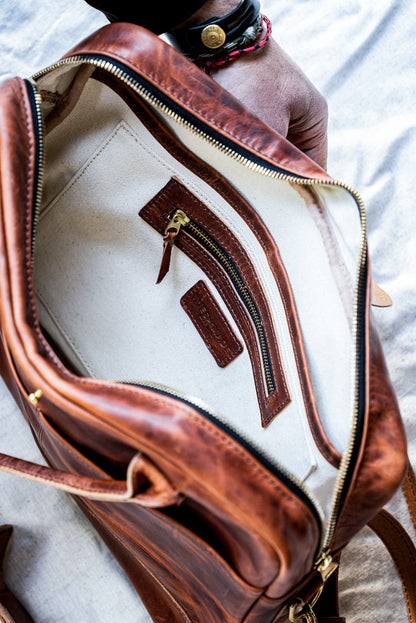 Interior of tan Horween leather briefcase with natural canvas lining and brass zip pocket.
