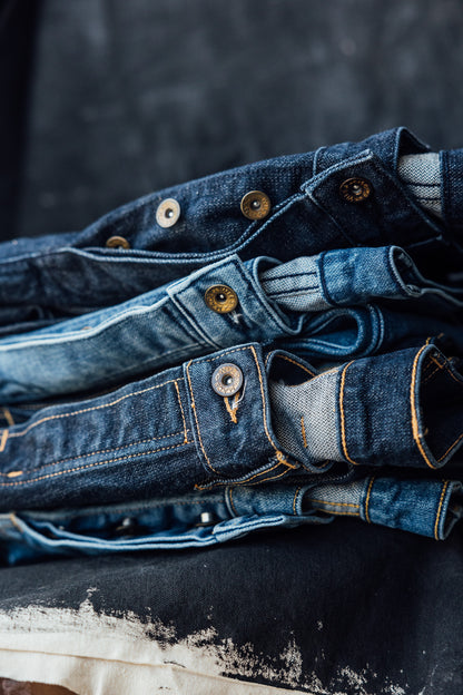 Stacked Sidney jeans showing button-fly closures with WiesMade brass rivets on 14oz denim.