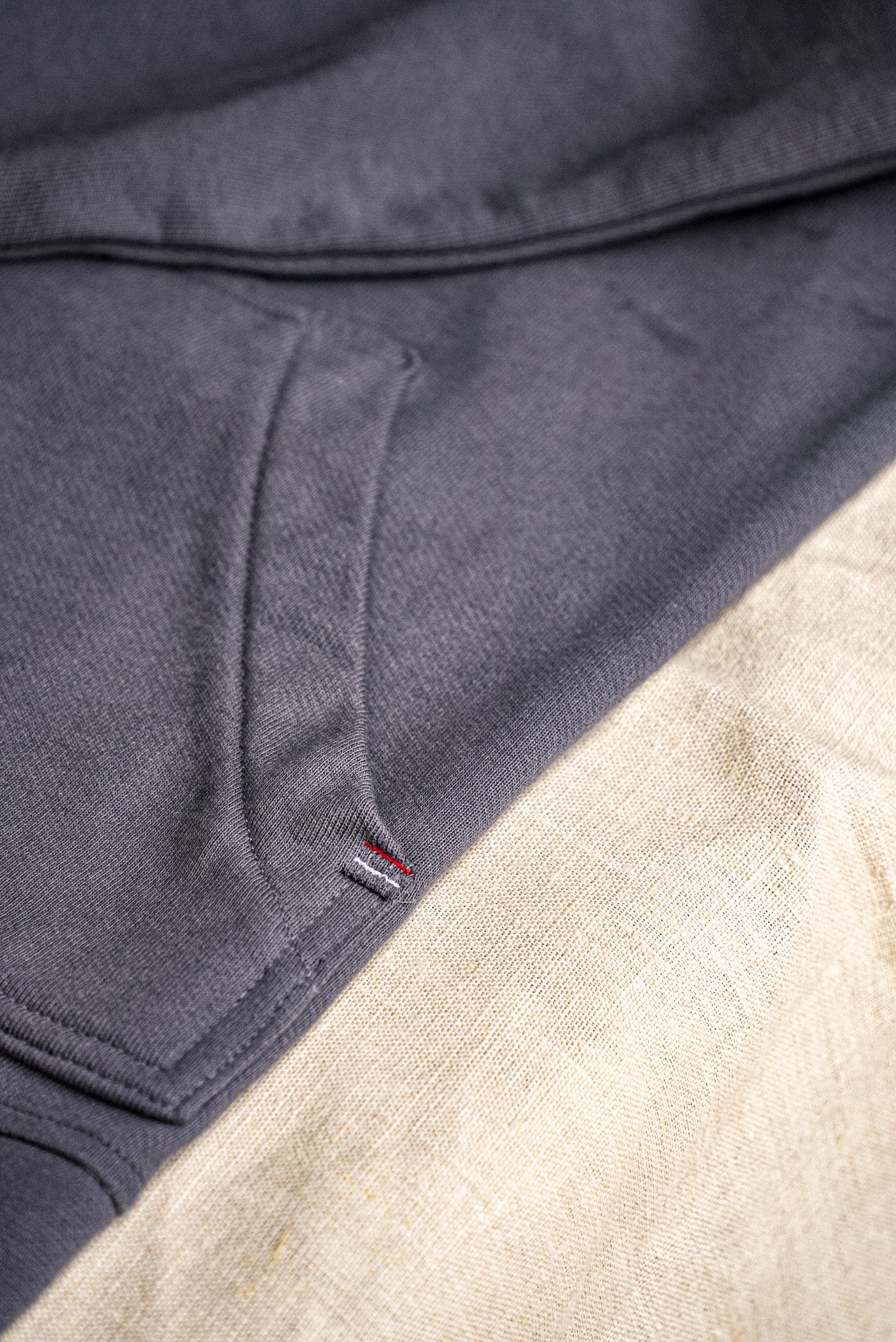 Close-up of pebble gray French terry cardigan showing diagonal knit texture, patch pocket, and woven tab detail.