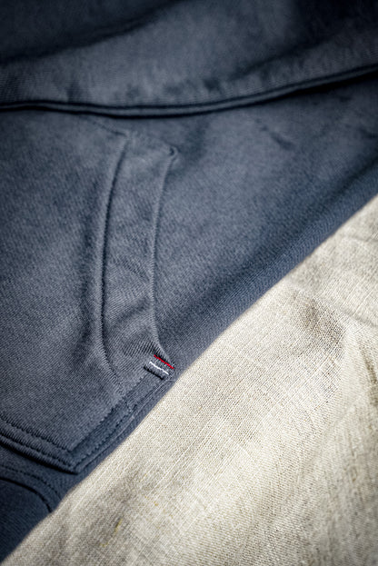 Close-up of the Bodega shawl cardigan's French terry knit and small woven flag label at the hem.