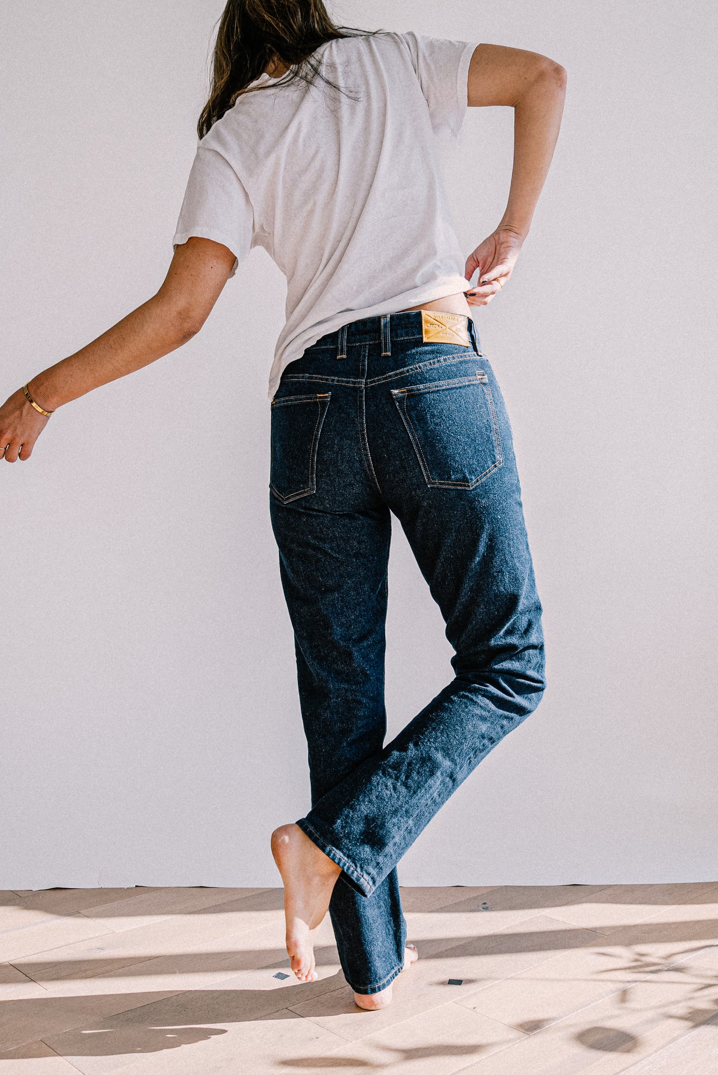 Back view of ocean wash mid-rise slim fit American made denim jeans paired with a white tee.