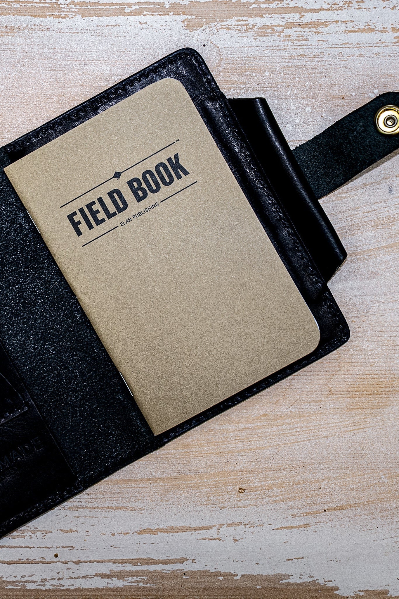 Open black Horween leather field notes cover holding a kraft Field Book notebook.