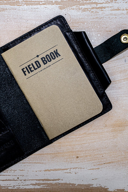 Open black Horween leather field notes cover holding a kraft Field Book notebook.
