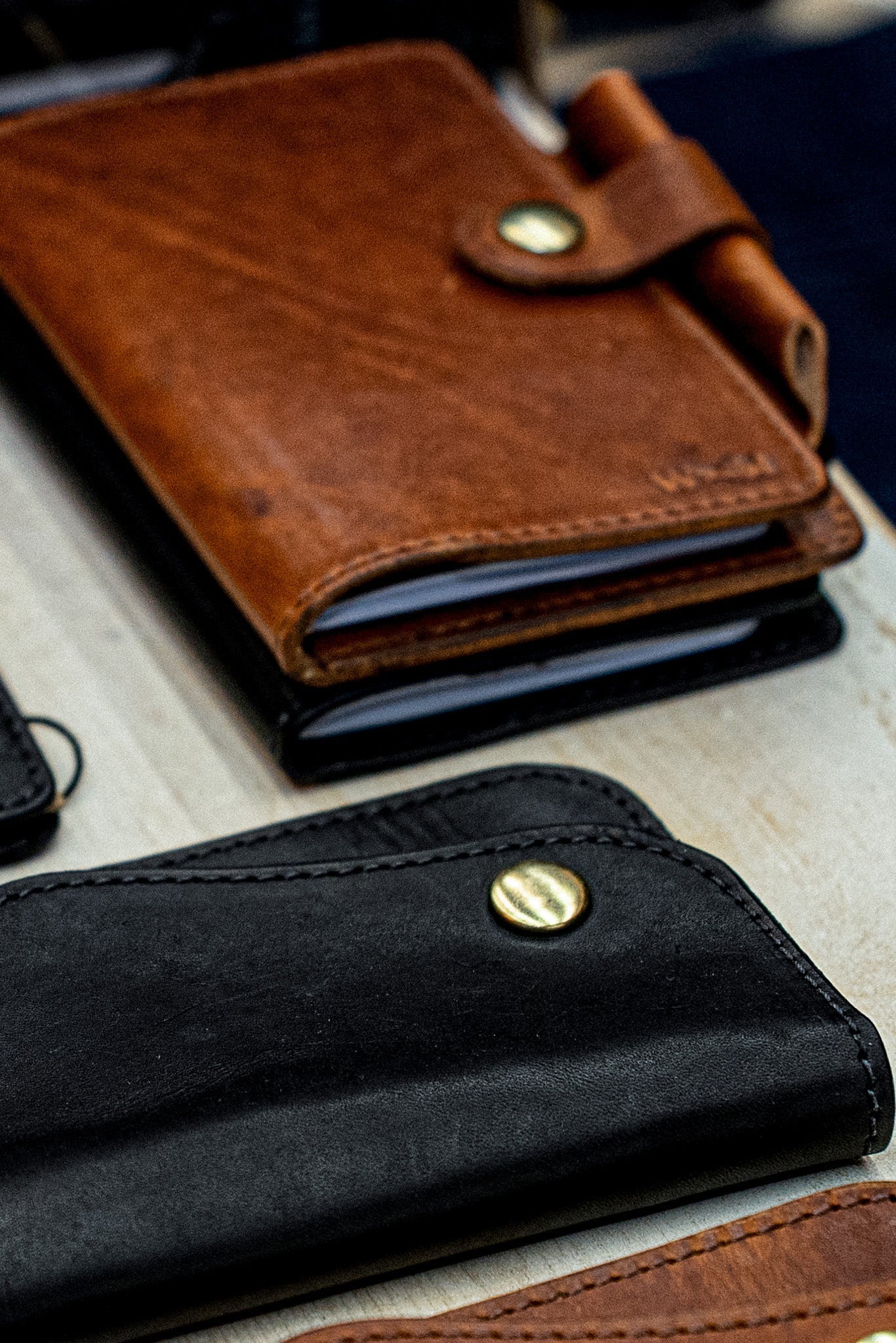 Brown and black Horween leather notebook covers with brass snap closures and pen loops.