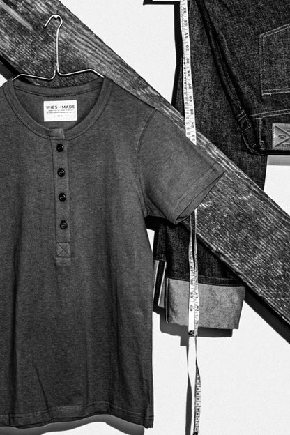 Navy four-button Reyes Henley on a hanger beside cuffed selvedge denim jeans and a tape measure.