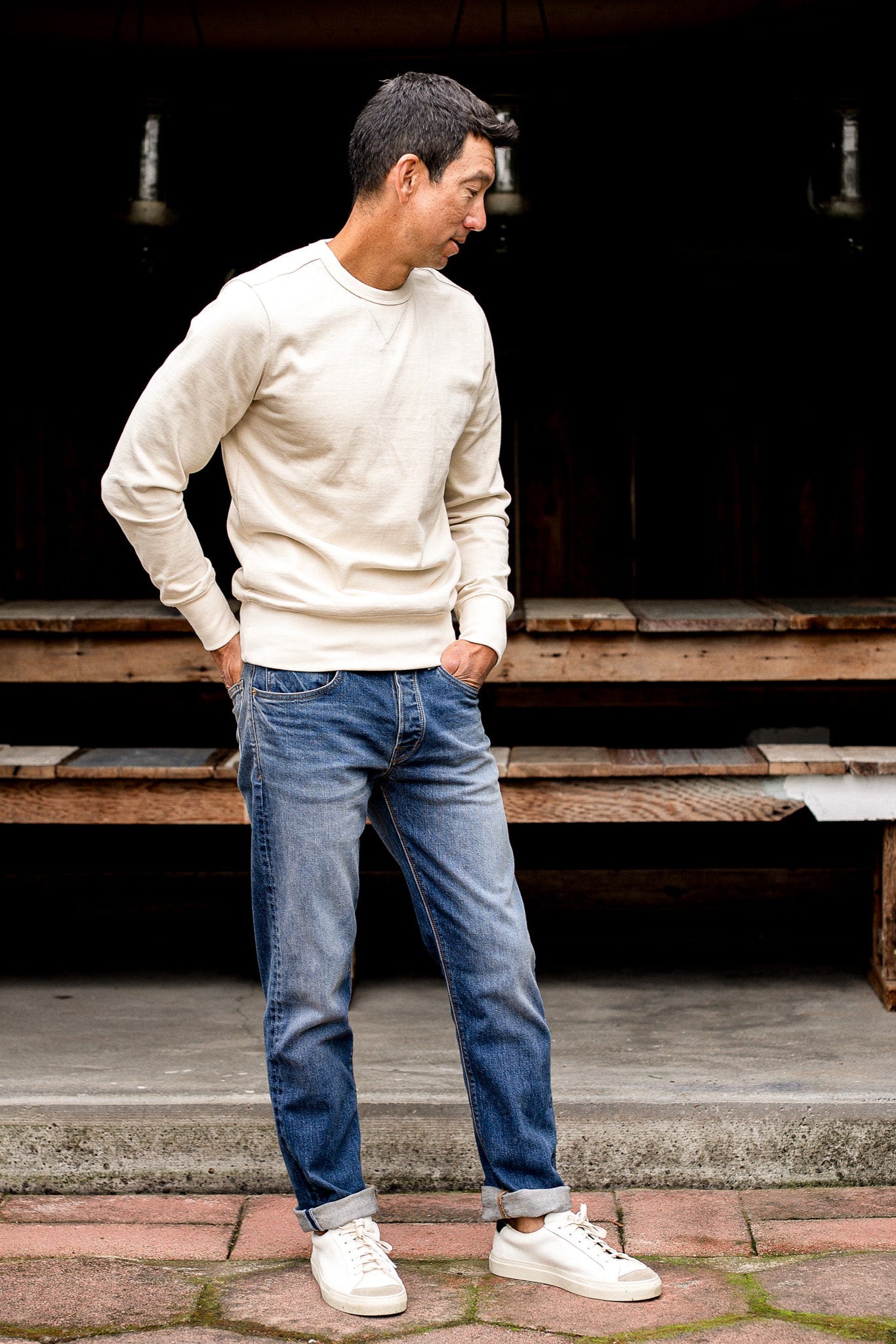 Man standing outdoors wearing loose straight cut denim jeans made in USA with a beige sweater