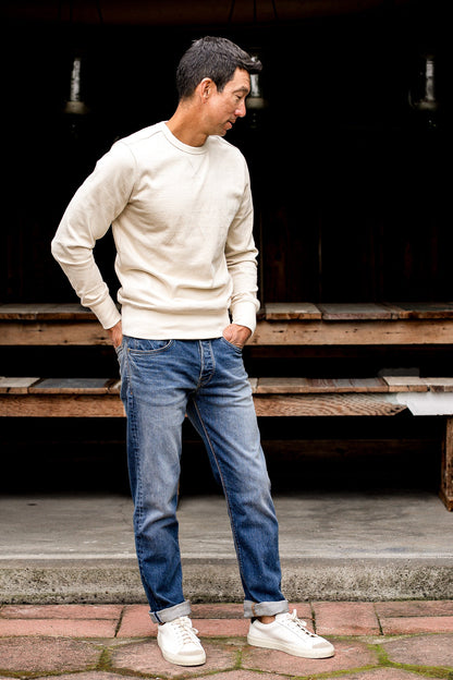 Man standing outdoors wearing loose straight cut denim jeans made in USA with a beige sweater