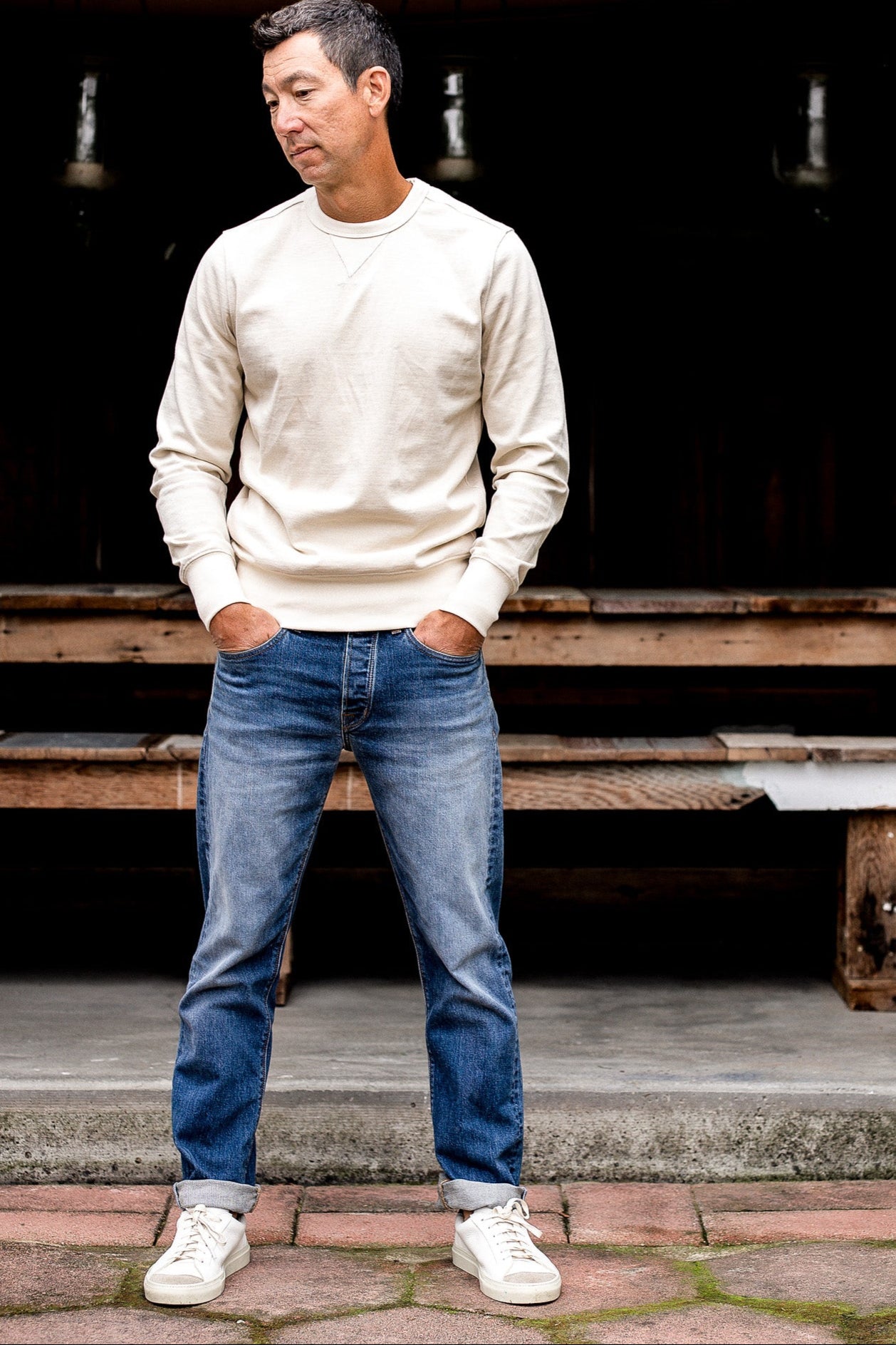 Man standing on steps wearing men's denim jeans made in USA with a beige sweater