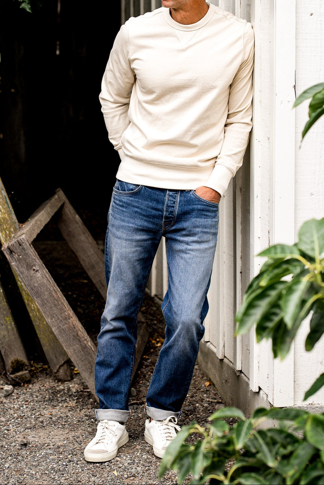 Man standing against a white wall wearing men's jeans made in USA with a white sweatshirt