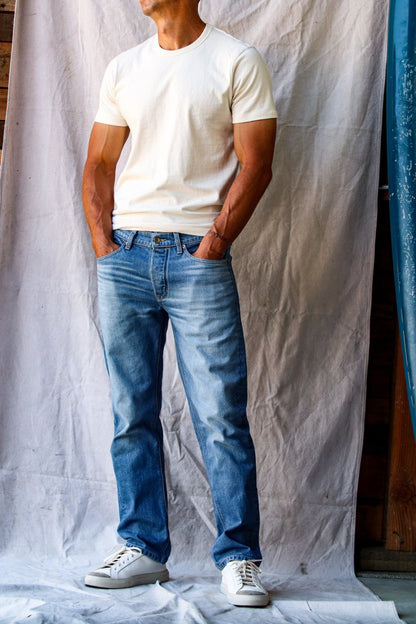 American denim jeans in a light wash, worn by a man with a white t-shirt and white sneakers.