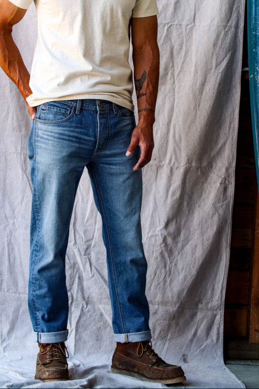 American made denim jeans in a light wash, worn with a white t-shirt and brown work boots.
