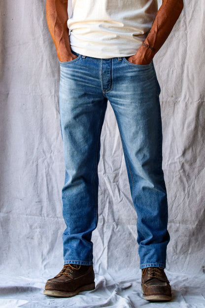 American Blues jeans in a light wash, styled with a white t-shirt and brown work boots for a classic casual look.