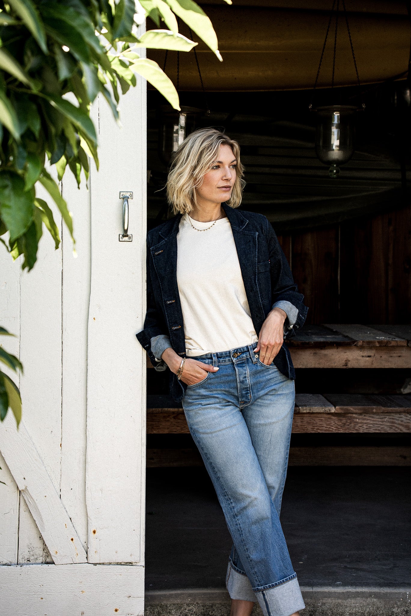 Women’s designer mid rise denim styled with a white top and dark denim jacket, featuring a relaxed straight leg fit, light wash finish, and cuffed hems