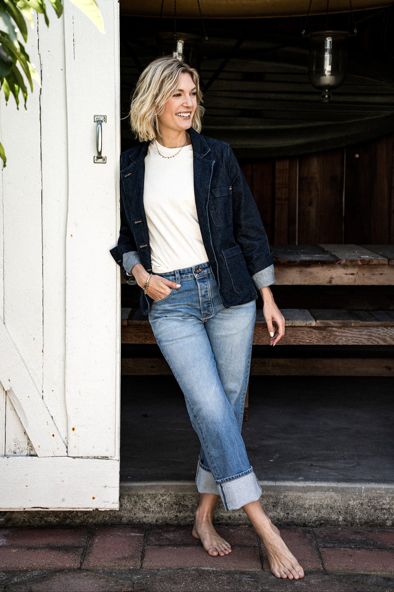 Women’s premium mid-rise jeans styled with a white top and dark denim jacket, featuring a relaxed fit, cuffed hem, and light blue wash for a casual, timeless look