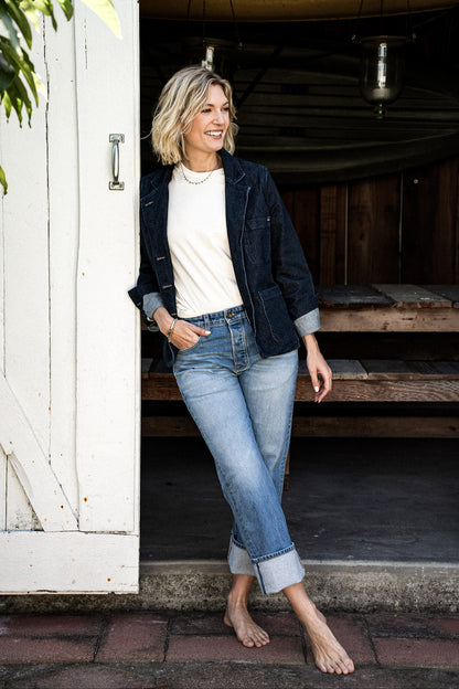 Women’s premium mid-rise jeans styled with a white top and dark denim jacket, featuring a relaxed fit, cuffed hem, and light blue wash for a casual, timeless look