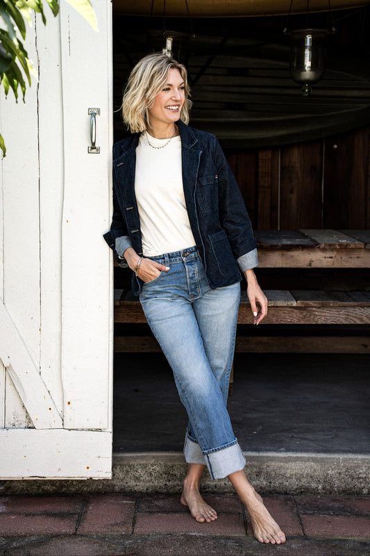 Women’s premium mid-rise jeans styled with a white top and dark denim jacket, featuring a relaxed fit, cuffed hem, and light blue wash for a casual, timeless look