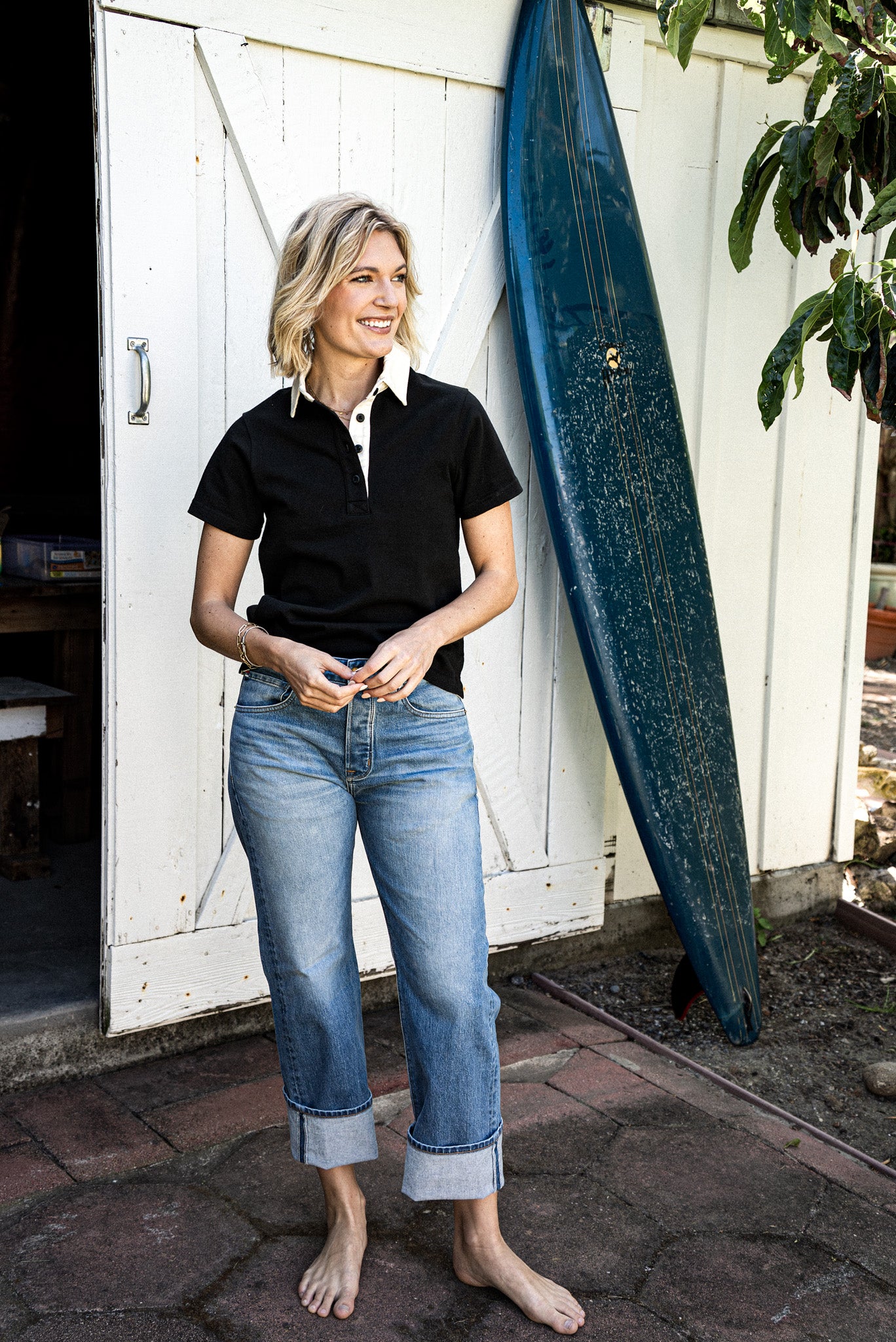 Women’s designer mid rise jeans styled with a black collared shirt, featuring a relaxed fit, light blue wash, and cuffed hems for a polished yet casual coastal look
