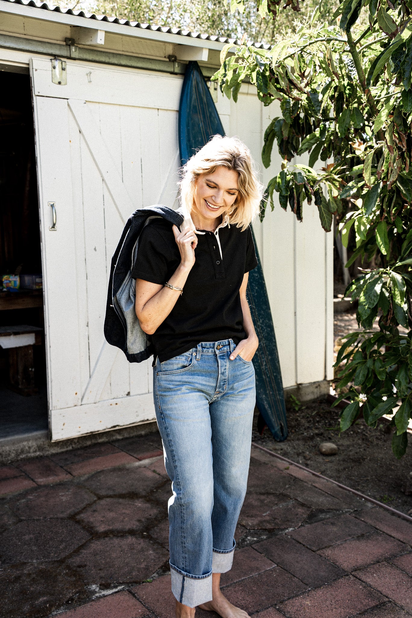 USA made women's jeans styled with a black collared shirt and denim jacket, featuring a mid rise fit, light blue wash, and cuffed hems for a relaxed, effortless look