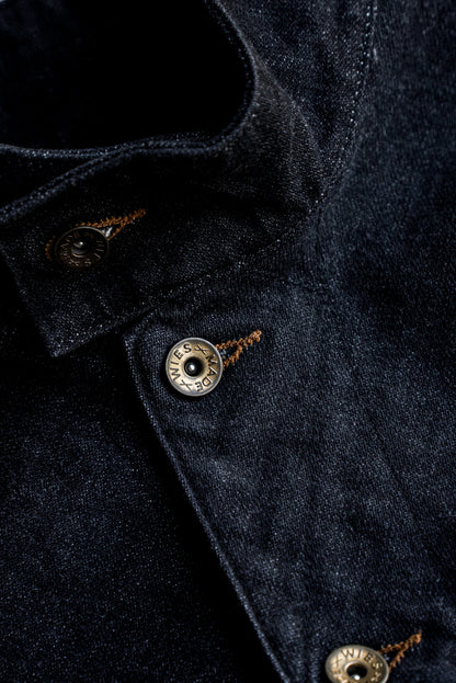 Close-up of black broken twill denim vest with brass WiesMade buttons and tobacco keyhole stitching.