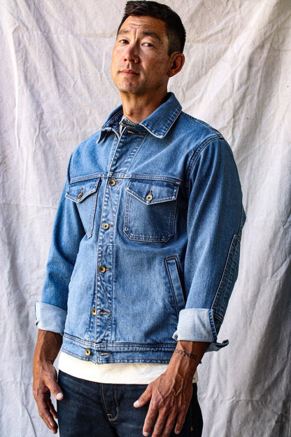 Made in USA denim jacket worn by a man standing against a neutral fabric backdrop.
