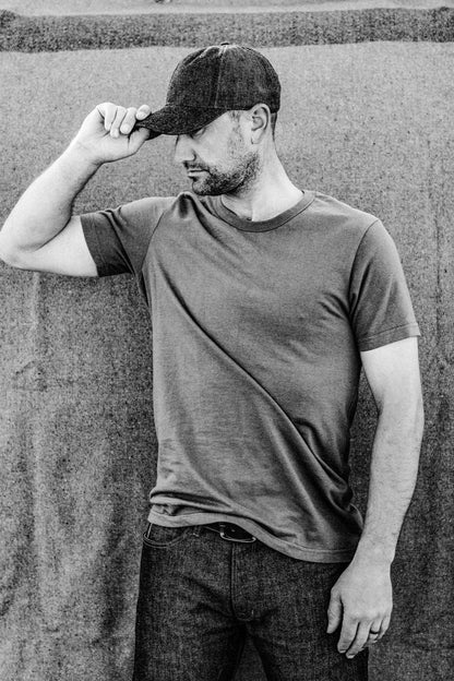 Man in olive Bolinas heavyweight cotton tee paired with raw denim jeans and a denim ball cap.
