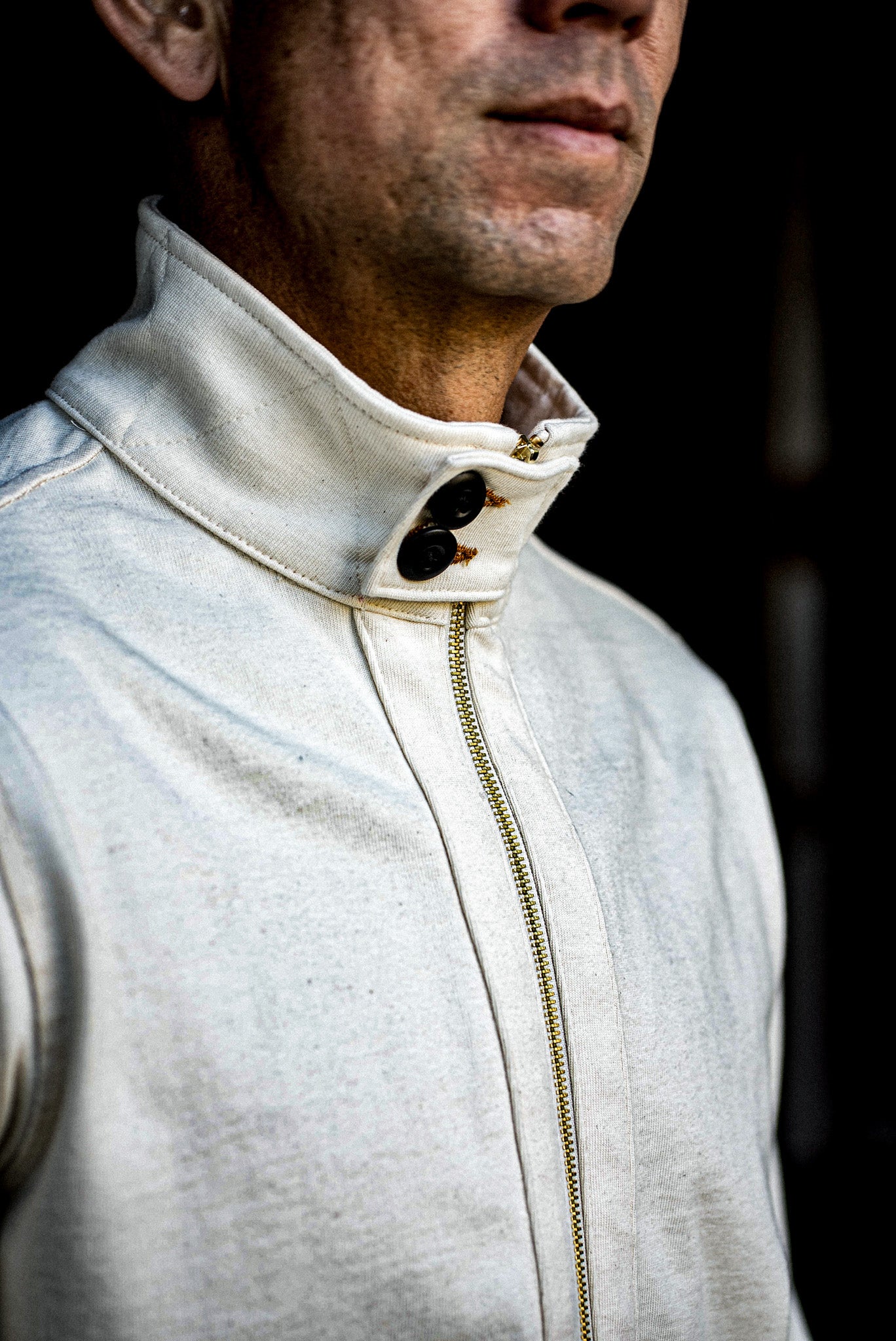 Natural cotton moto zip jacket with brass zipper and buttoned stand collar on a man.