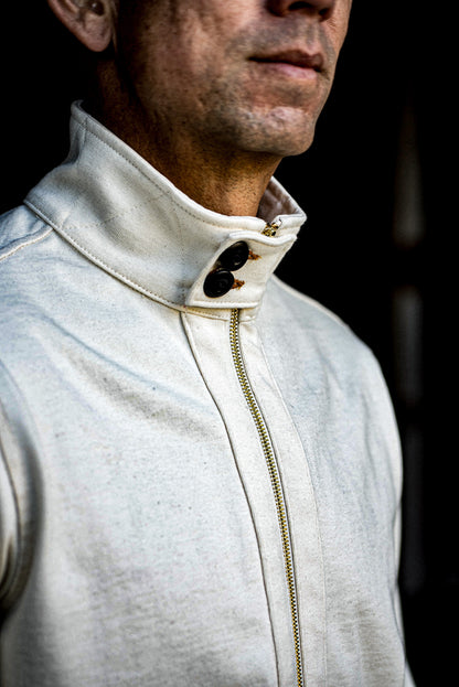 Natural cotton moto zip jacket with brass zipper and buttoned stand collar on a man.