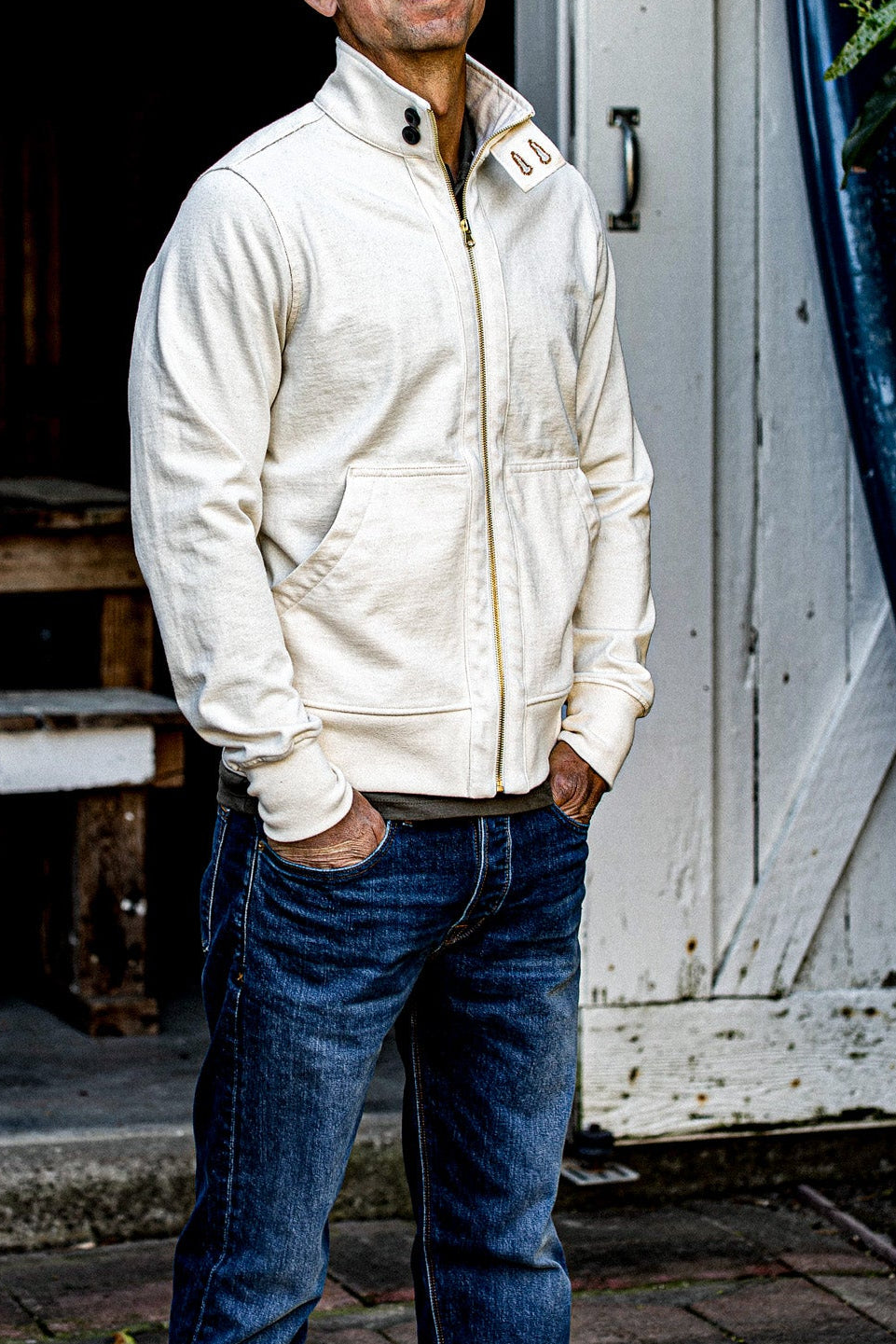 Man wearing a natural cotton Stinson moto zip jacket with brass zipper over jeans.