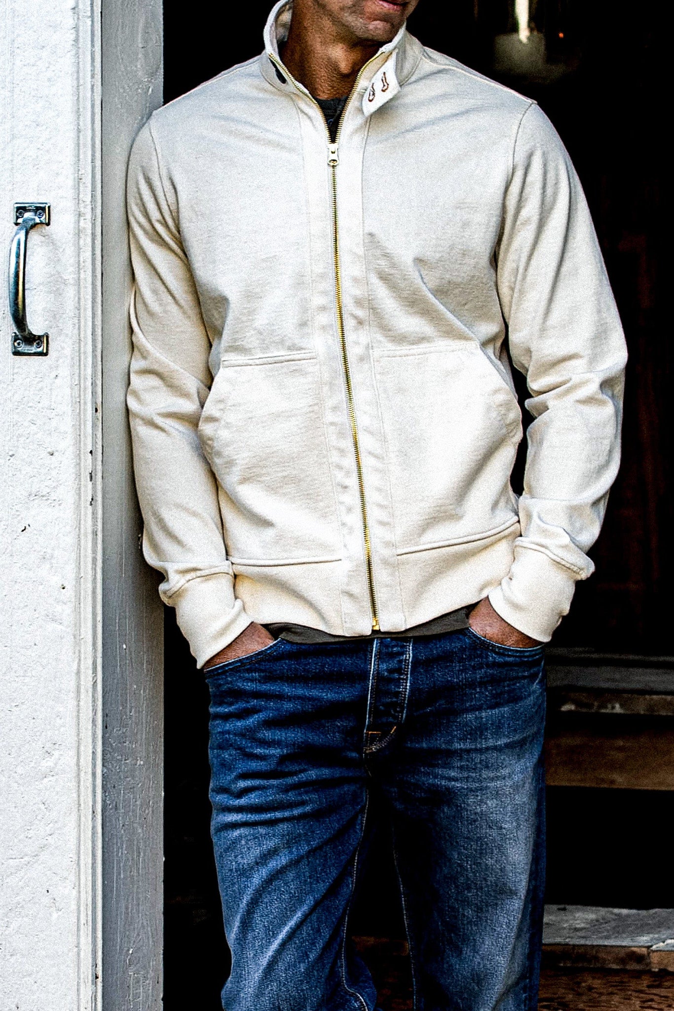 Natural cotton Stinson moto zip jacket worn open over jeans against a doorway.