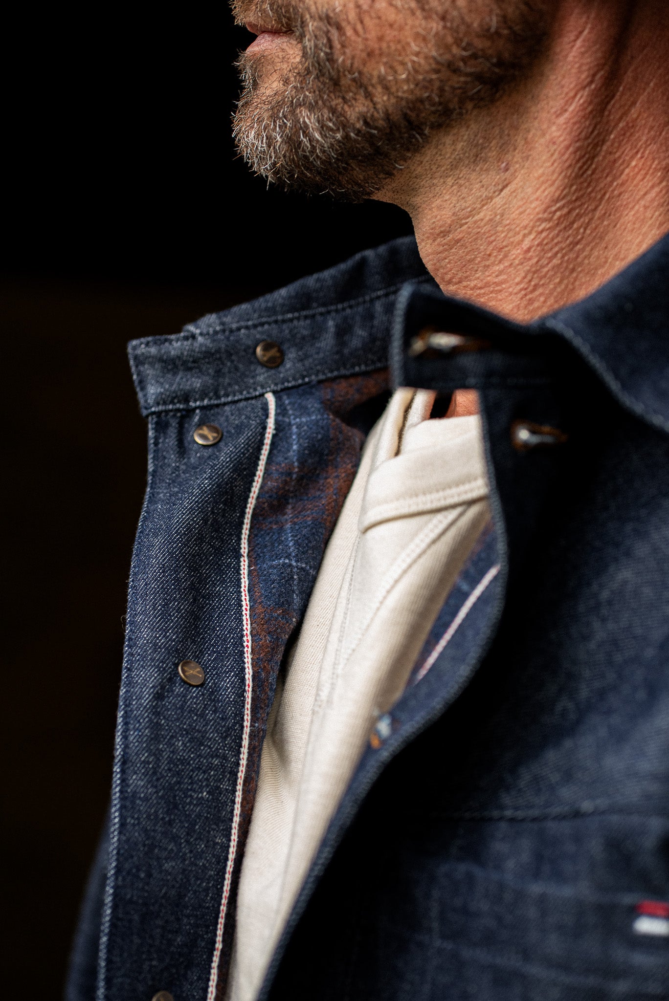 Close-up collar detail of WiesMade Nico indigo jacket showing selvedge seam and cream turtleneck underneath.