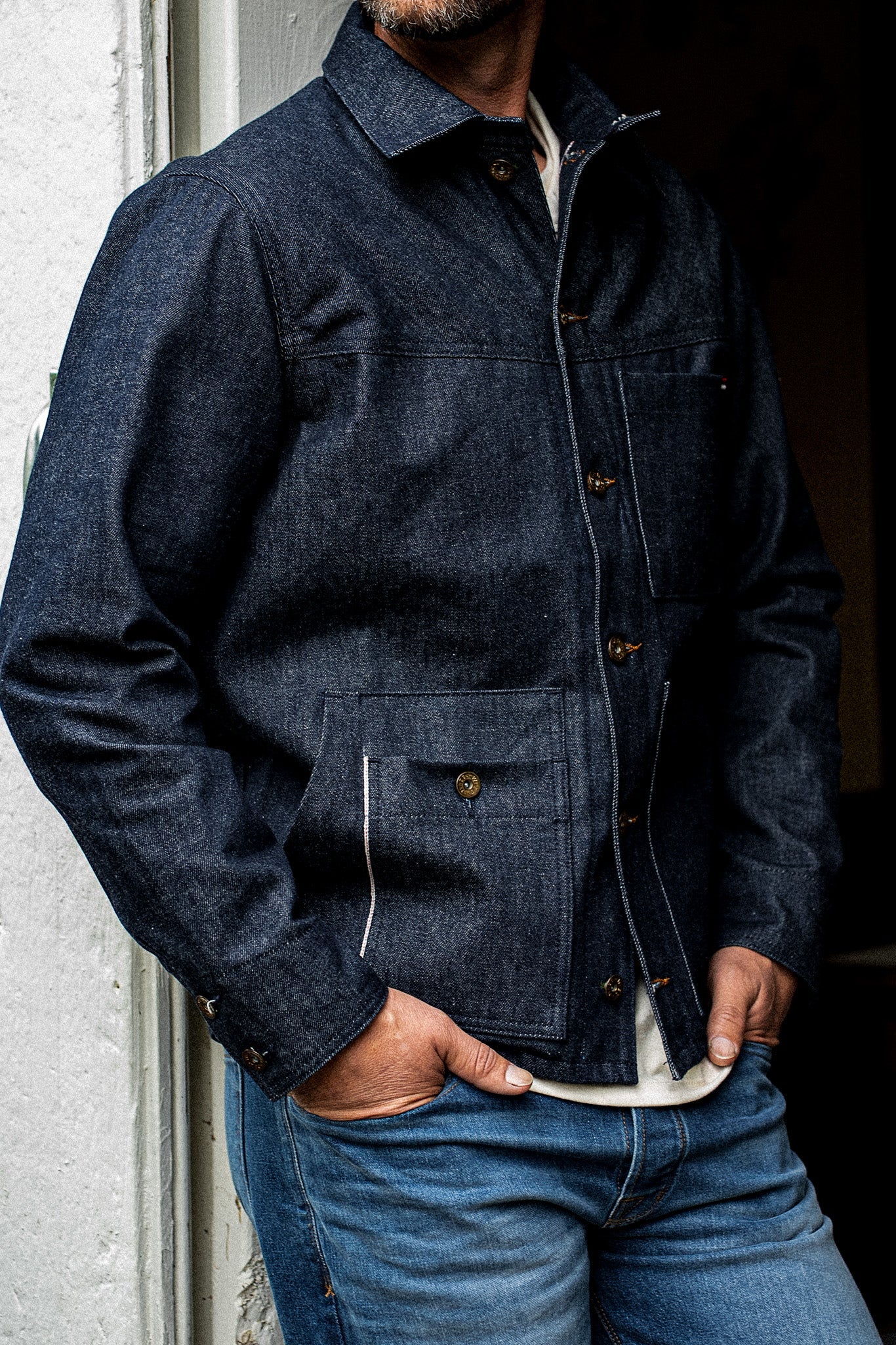 Front torso view of man wearing the WiesMade Nico indigo denim jacket open over a white tee and faded jeans.