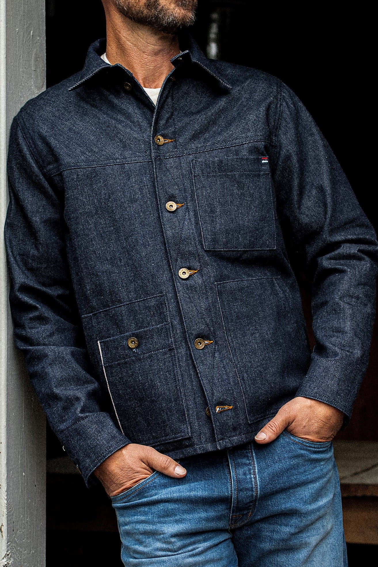 WiesMade Nico indigo denim jacket buttoned on a model showing chest pockets and brass button closure.