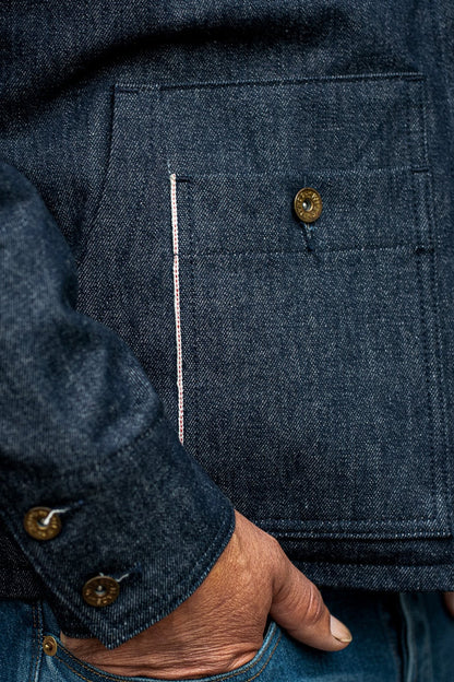 Close-up of WiesMade Nico indigo jacket pocket with brass button, selvedge trim, and rolled cuff detail.