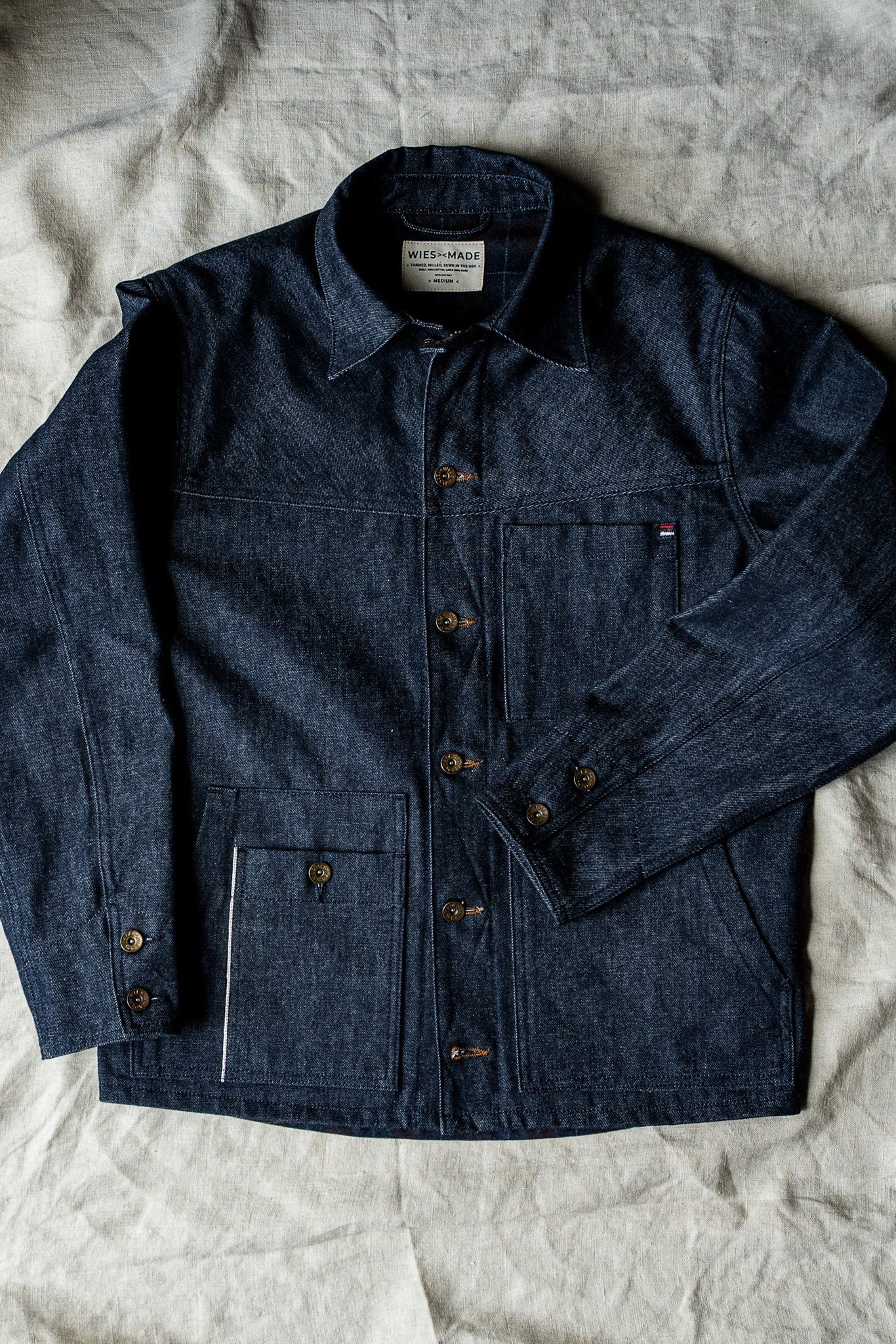 WiesMade Nico indigo denim jacket full flat lay showing four-pocket design, brass buttons, and brand label.